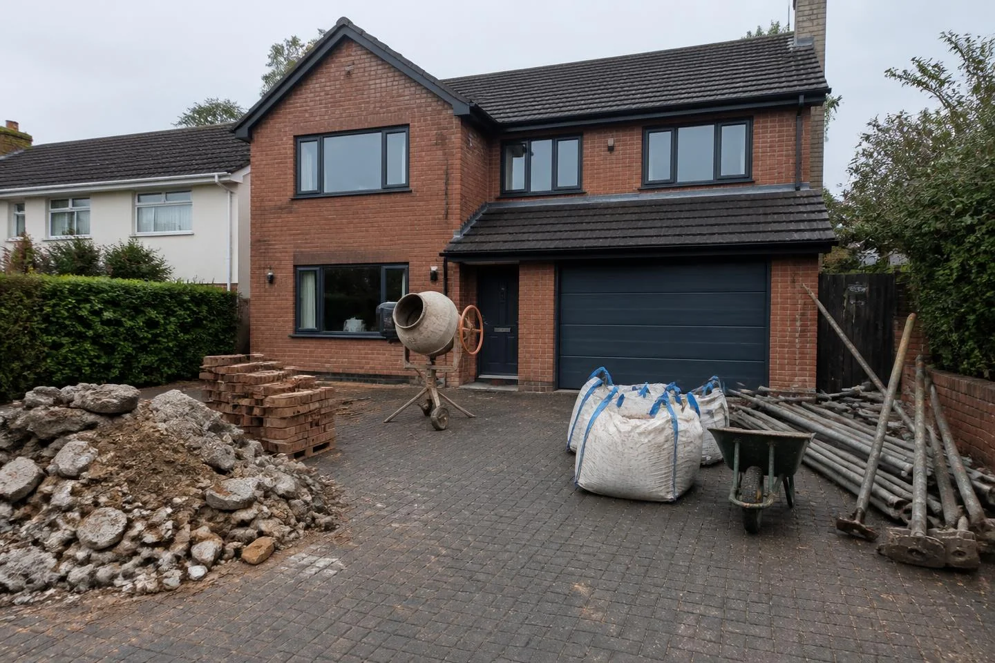 Driveway covered in rubble, bricks, a cement mixer and scaffold poles before AI Clear Exterior Space