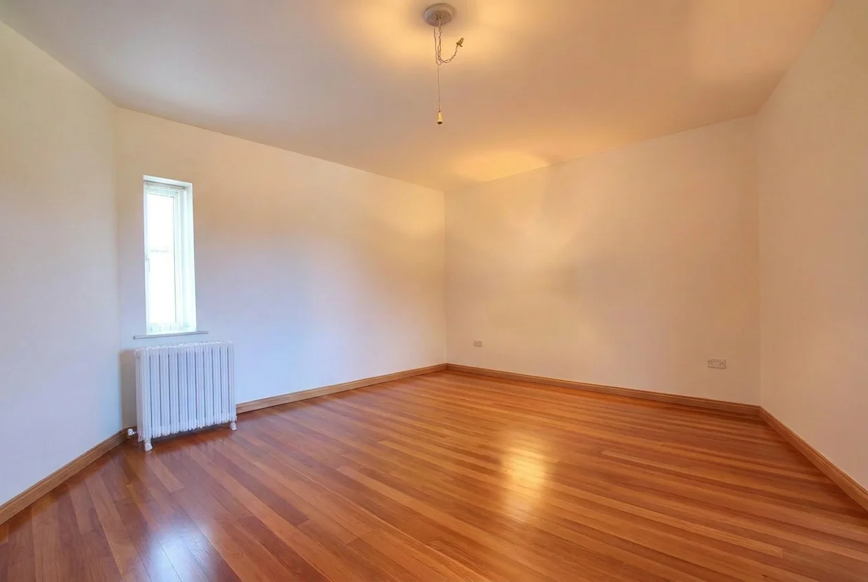 Empty bedroom with bare walls and wooden floor after AI Empty Room Generator