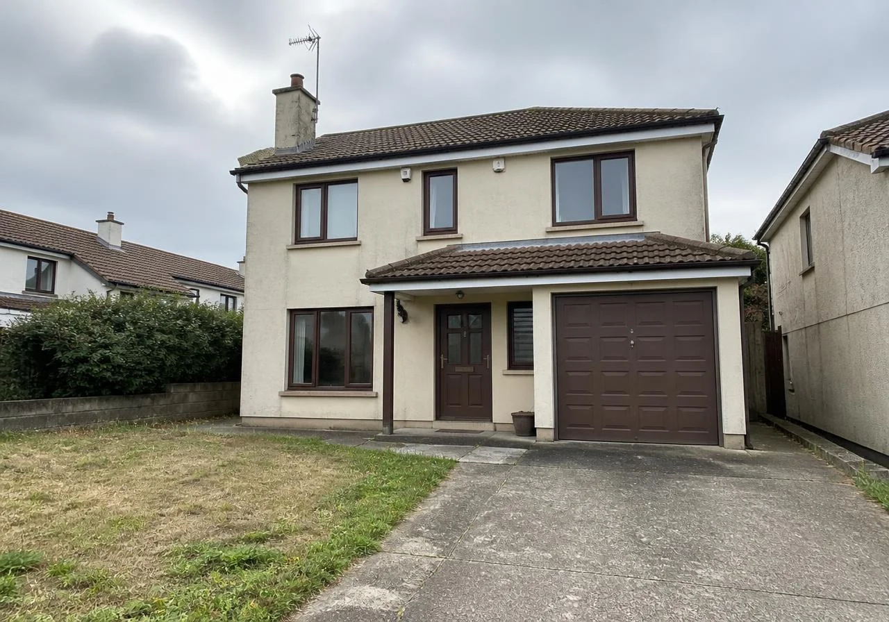 Dated 1990s family house with beige stucco, brown windows and a dry lawn