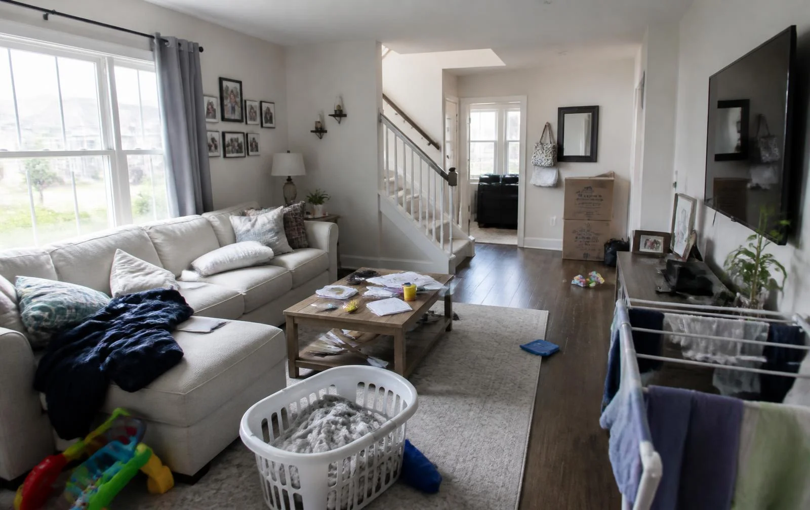 Cluttered family living room with laundry, toys and boxes before AI virtual decluttering